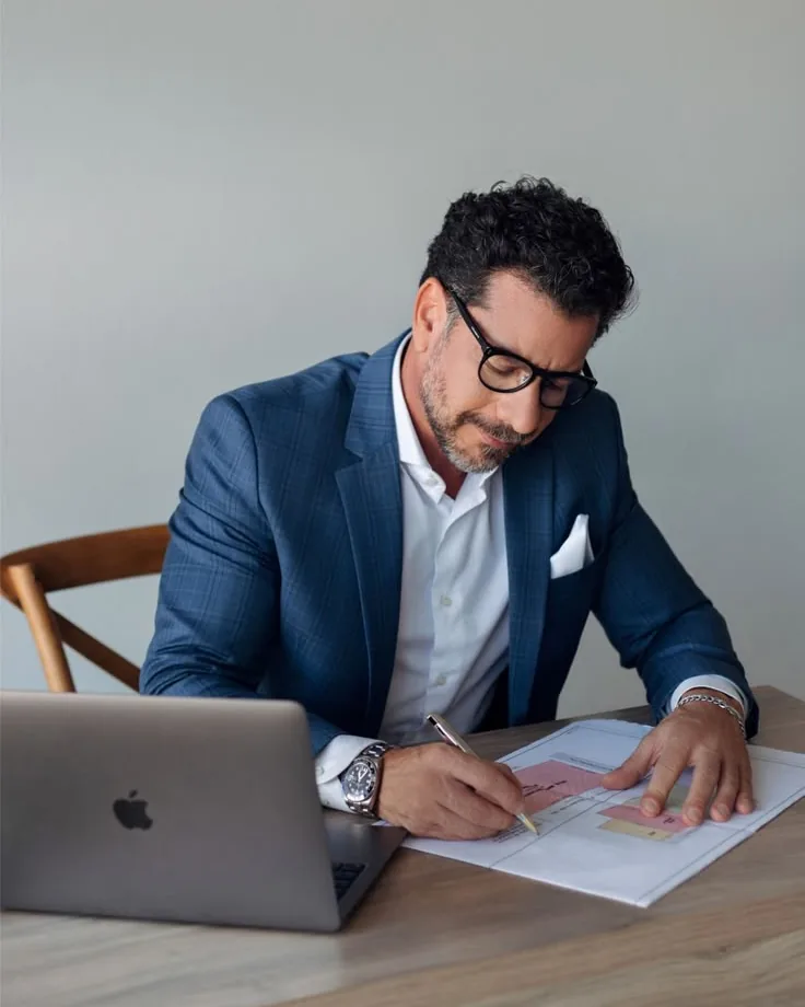 A consultant reviewing documents at a desk beside a laptop